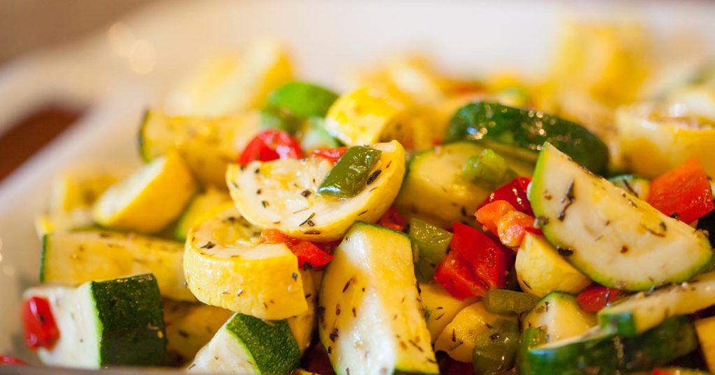 Serving bowl with herbed zucchini and yellow squash with sweet peppers